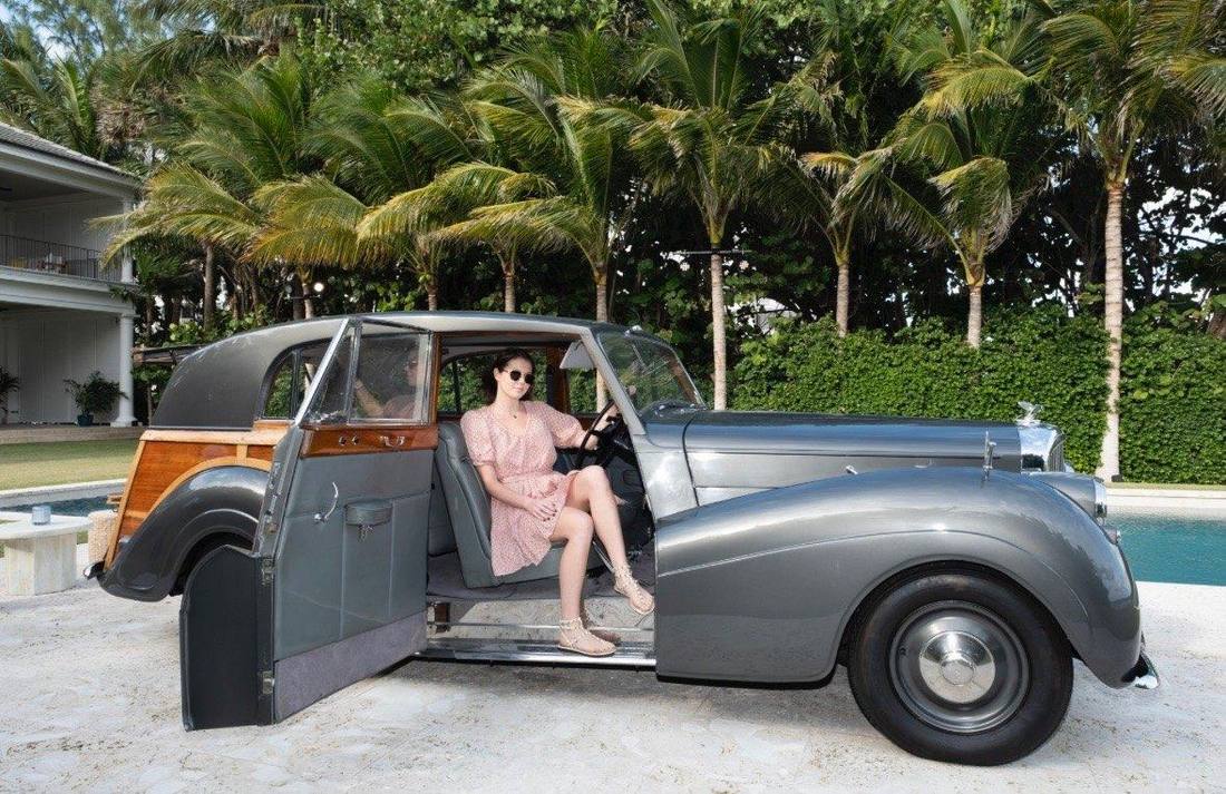 Seated in the open door of a vintage car