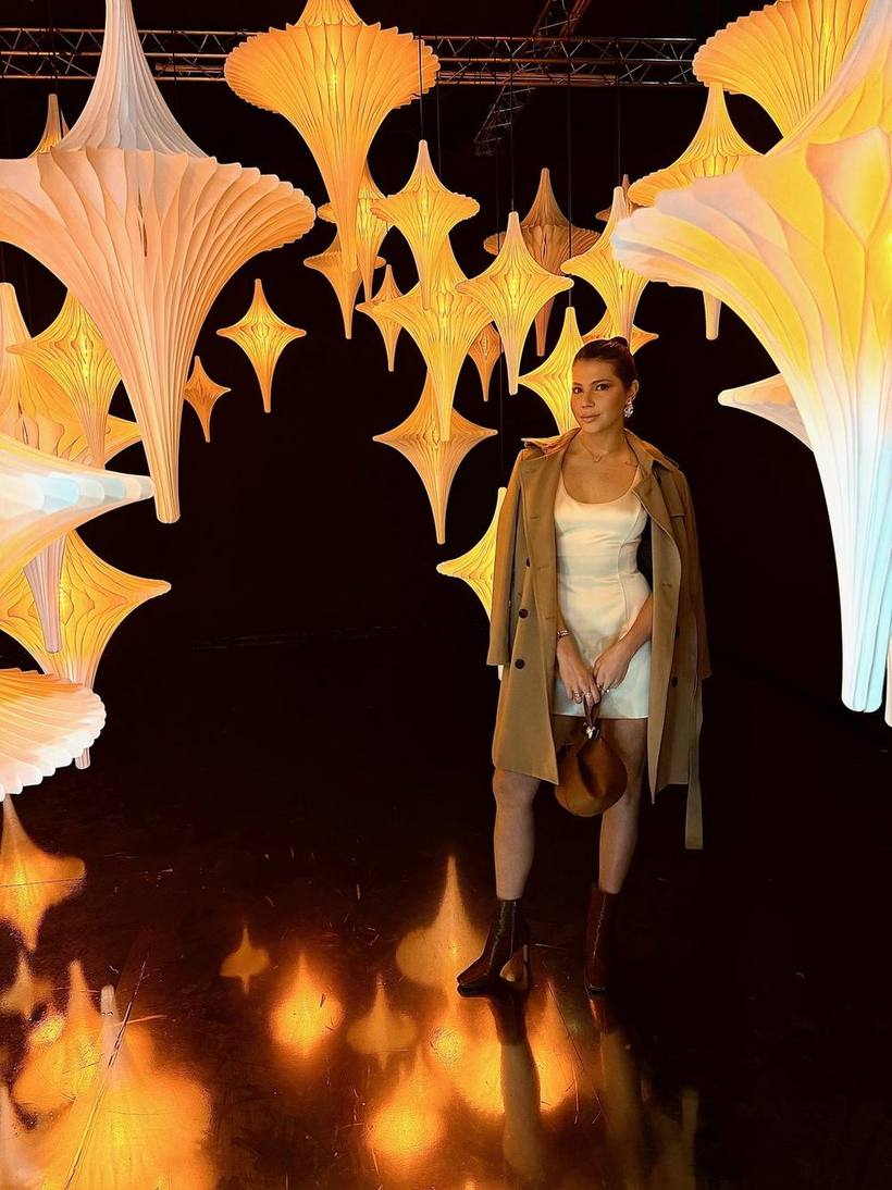Satin slip dress and trench coat among illuminated sculptures