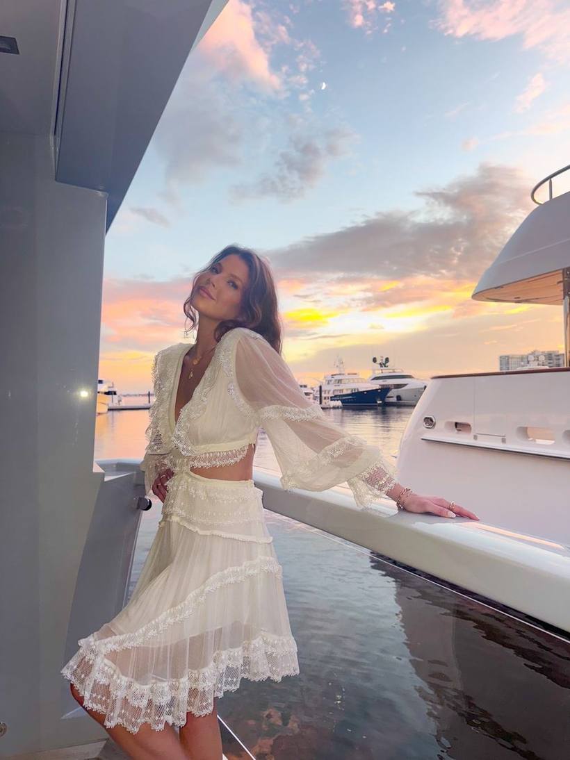 Leaning on a yacht rail at sunset in white lace